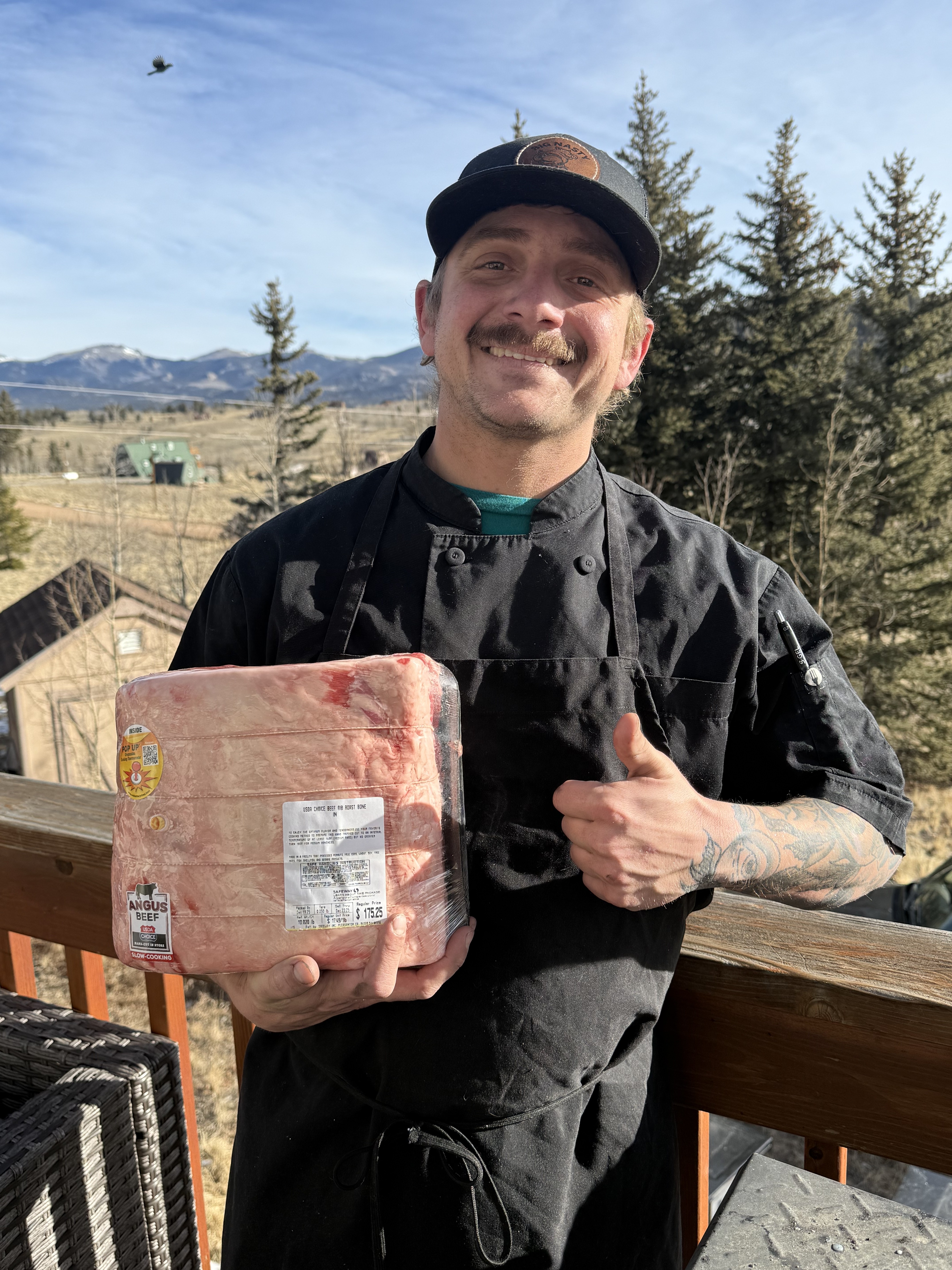 Stephen holding a USDA Choice bone-in rib roast on a Colorado mountain deck